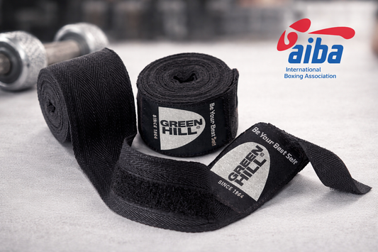 Fasce da boxe nere Green Hill arrotolate con logo AIBA su sfondo palestra, vista orizzontale